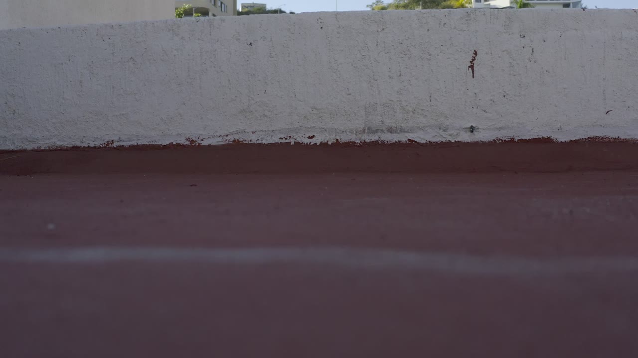 White stucco parapet and red rooftop surface in Los Cabos, with no visible people in this opening frame.