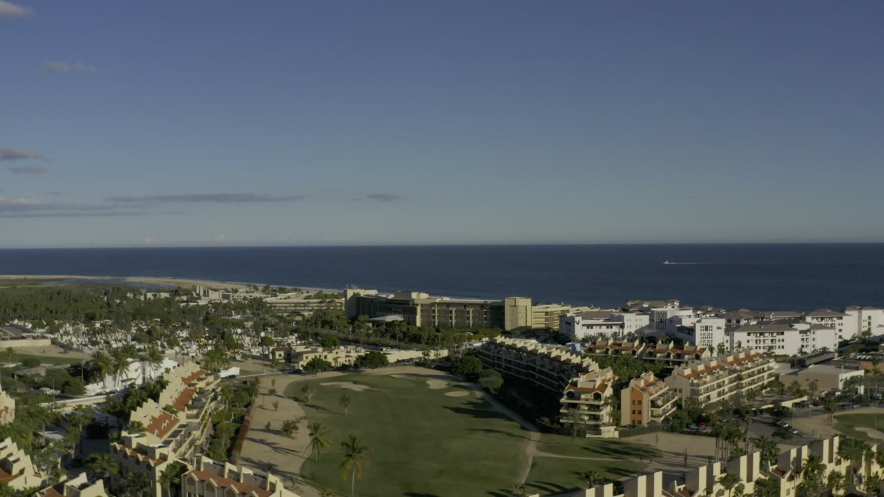 Aerial view of coastal buildings, beach, ocean, and clear sky.
