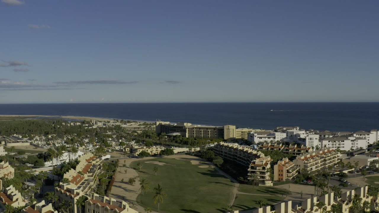 Aerial view of resort lawns, homes, hotel buildings, and ocean horizon.