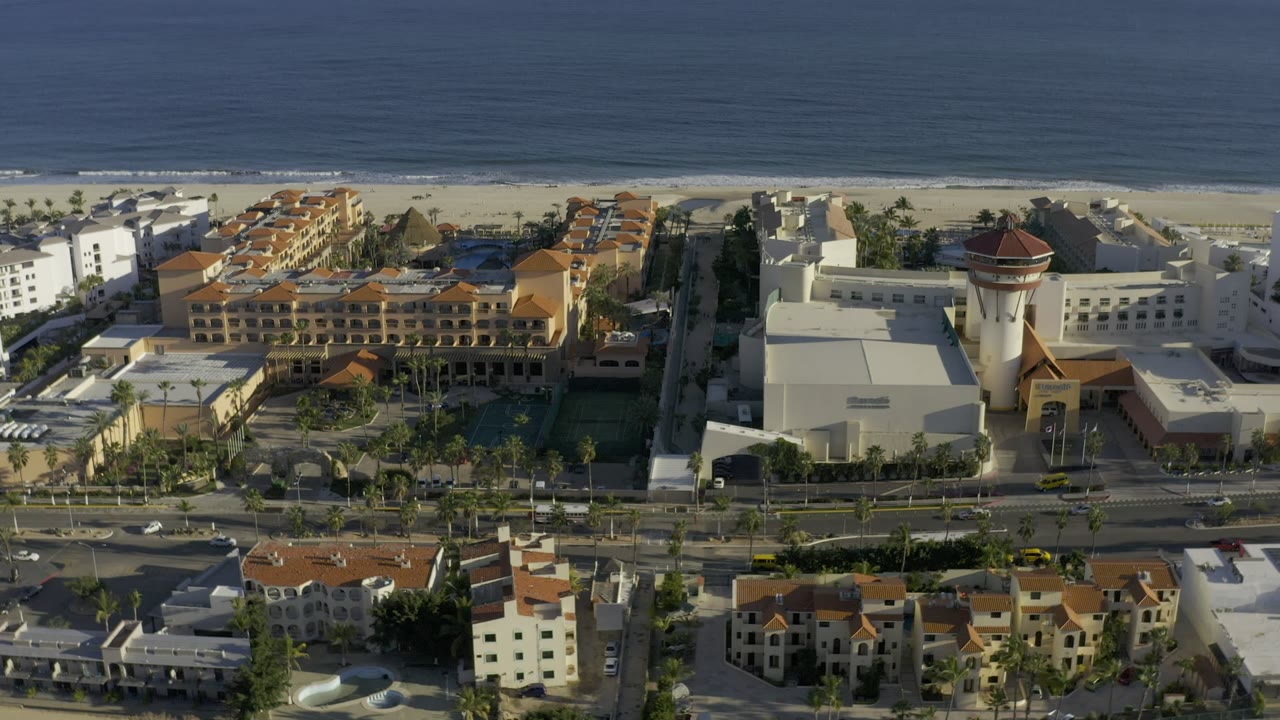 Aerial view of beachfront buildings, road traffic, beach, and ocean.