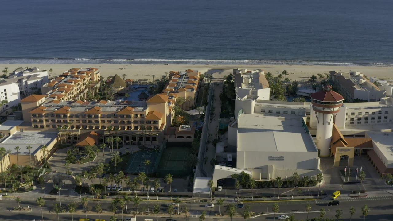 Aerial view of beachfront buildings beside a sandy beach and ocean.