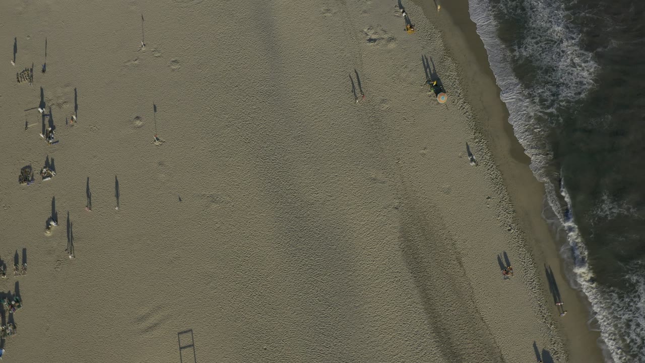 Overhead beach shoreline with surf and scattered small figures