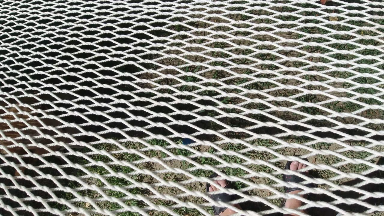 White rope net over grass with partial feet below