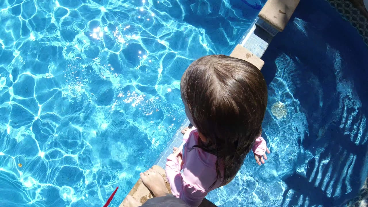 Top-down frame of the child beside the pool edge, with bright ripples and reflections filling the water in San Jose Del Cabo, Mexico.