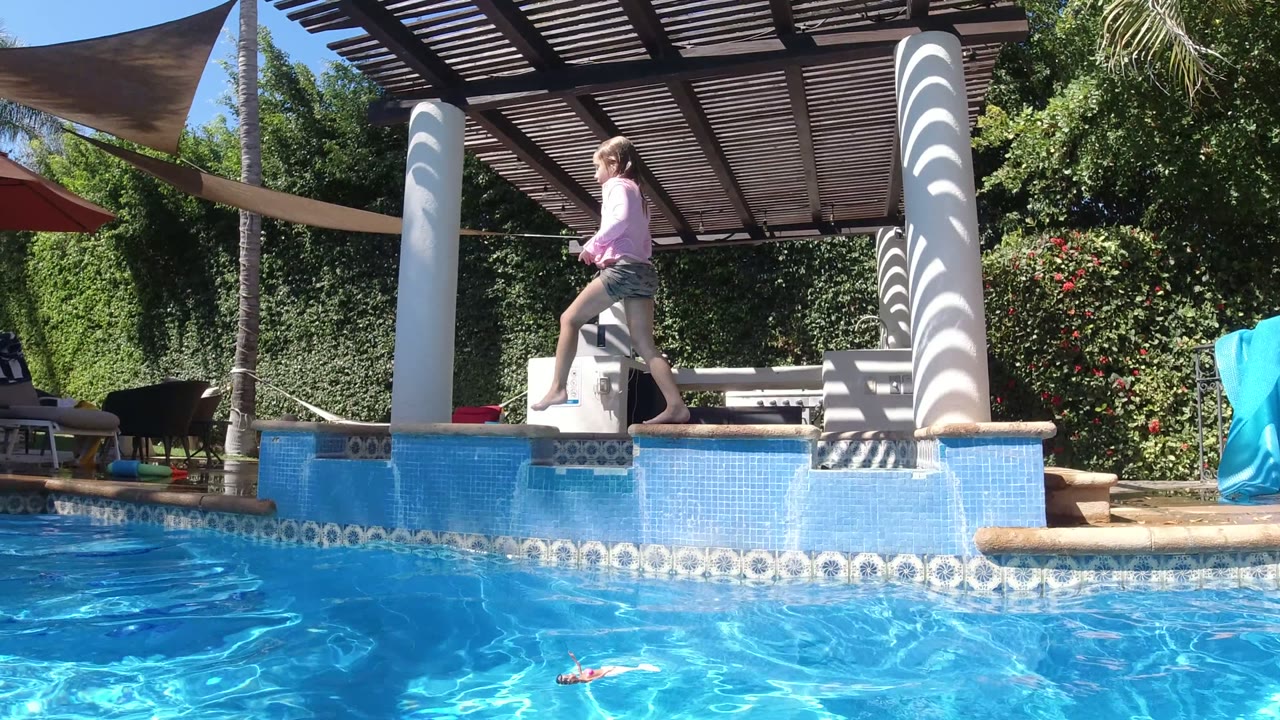 Girl stepping past a white poolside column.