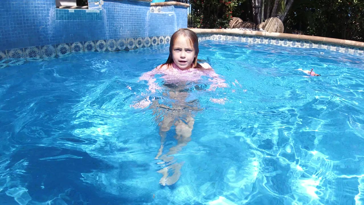 Young girl facing camera in a bright blue swimming pool.
