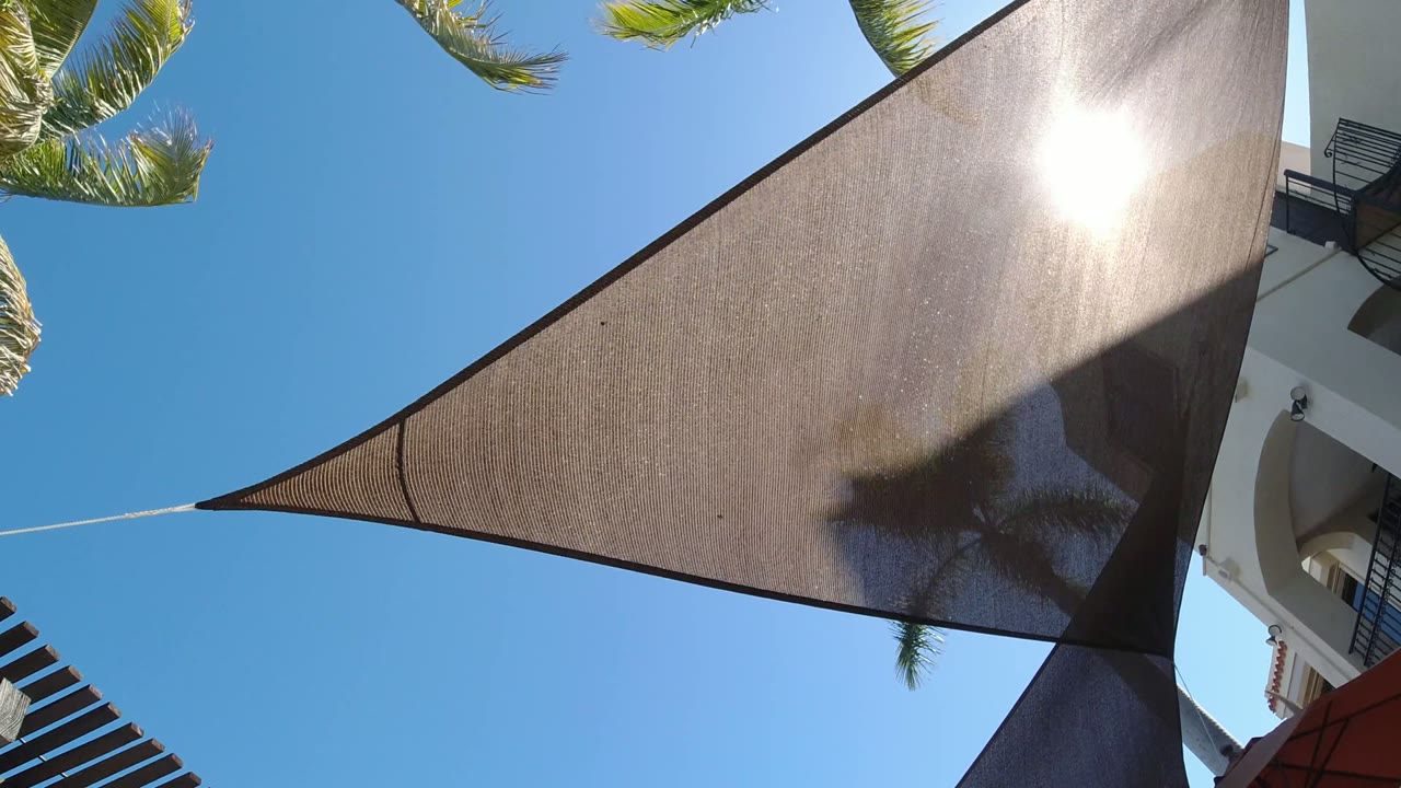 Dark triangular shade cloth under bright sun and blue sky