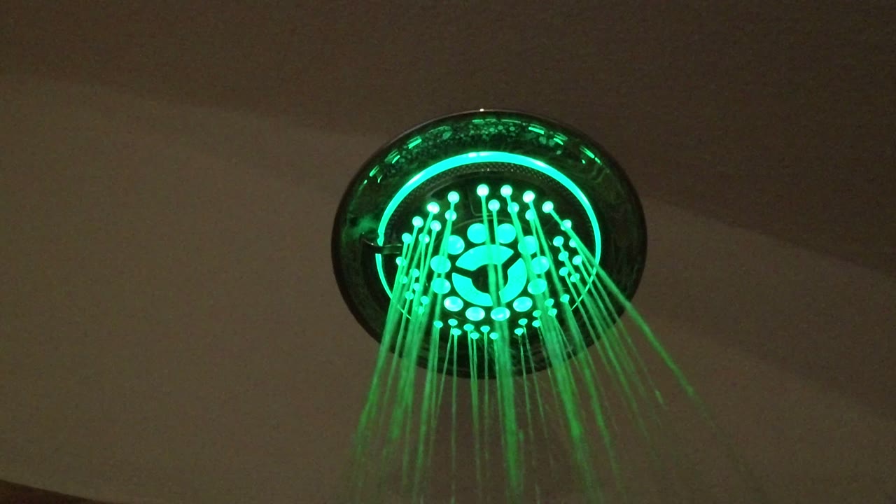 At 0:00, a green-lit round shower head sprays thin streams of water in San Jose del Cabo, Mexico, with no visible people.