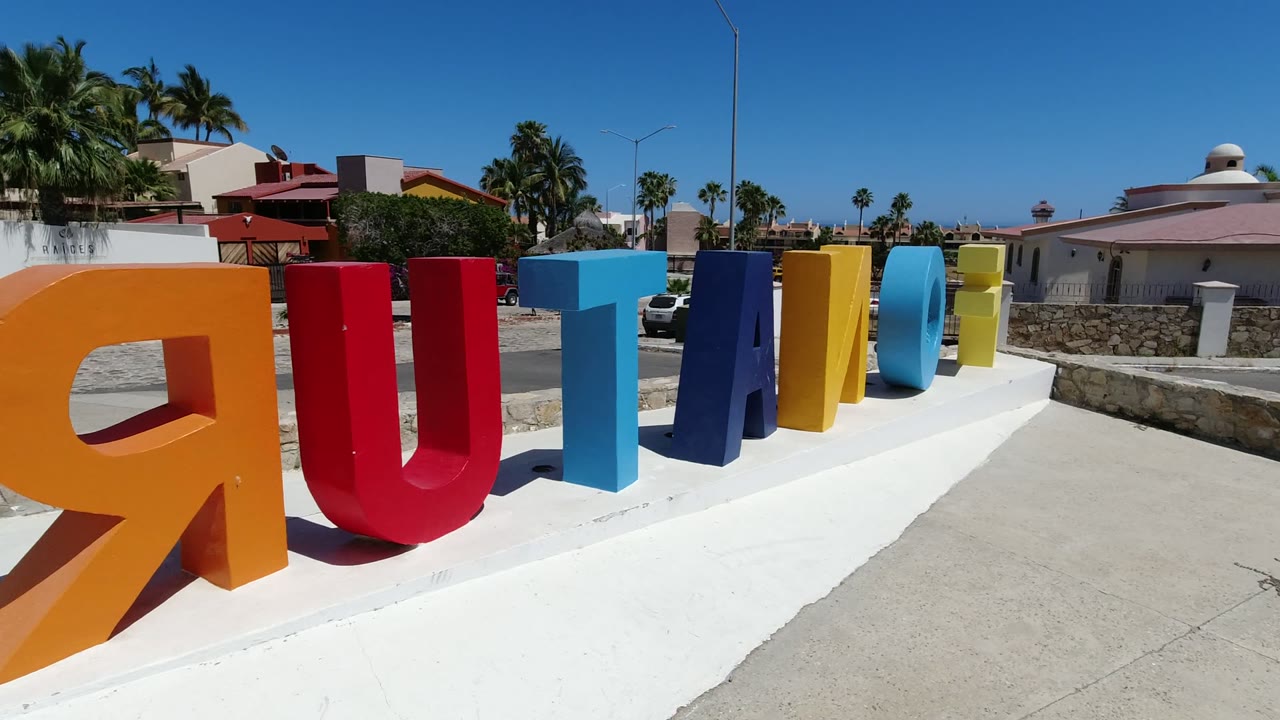 Closer angle on the orange and red letters in Los Cabos, Mexico, with the remaining blue and yellow letters receding to the right and no visible people.