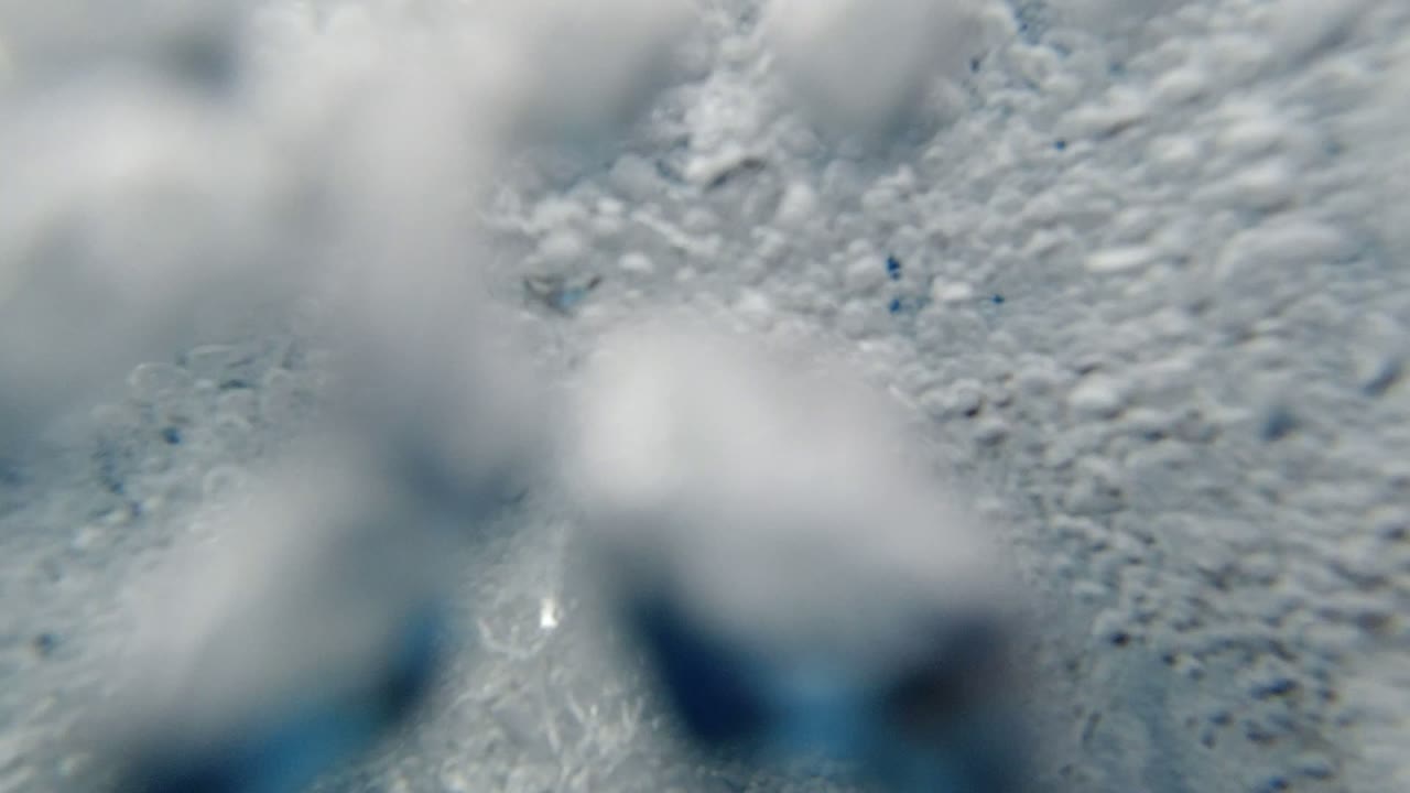 Soft-focus bubbles drift across a rippled underwater surface in Los Cabos, Mexico, with bright white foam dominating the frame and no visible people.
