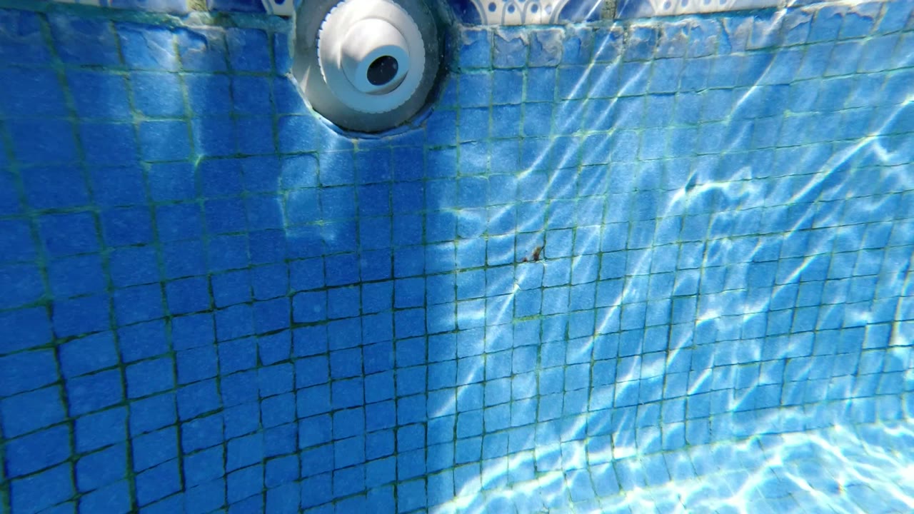 One second into the Los Cabos clip, the pool jet remains near the upper edge while rippled light bands move across the blue tiled wall and no visible people appear.