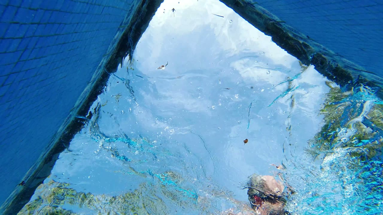 Blue reflective glass with clouds, a diagonal dark edge, and a partial person at the bottom.