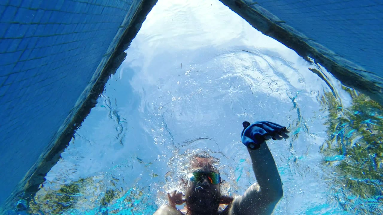 Goggled swimmer seen from below the water surface.