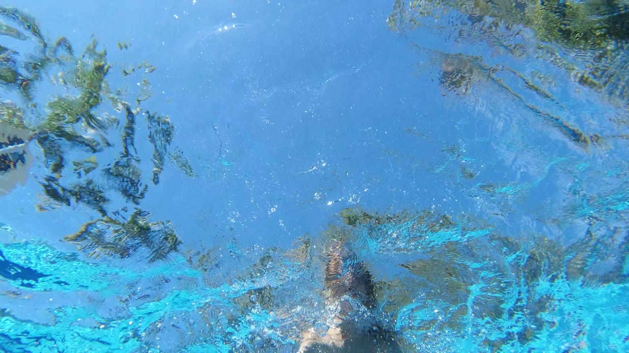 Underwater pool view with a swimmer partly entering the frame