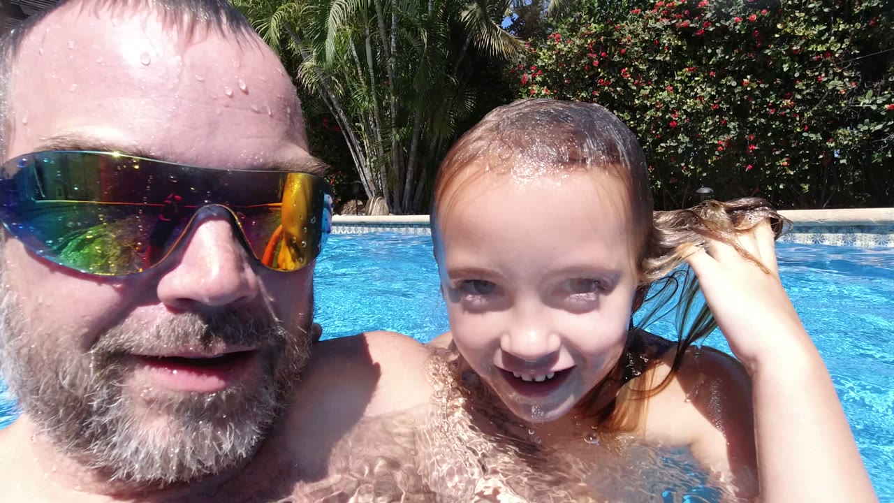 Adult man and young child smiling in a swimming pool.