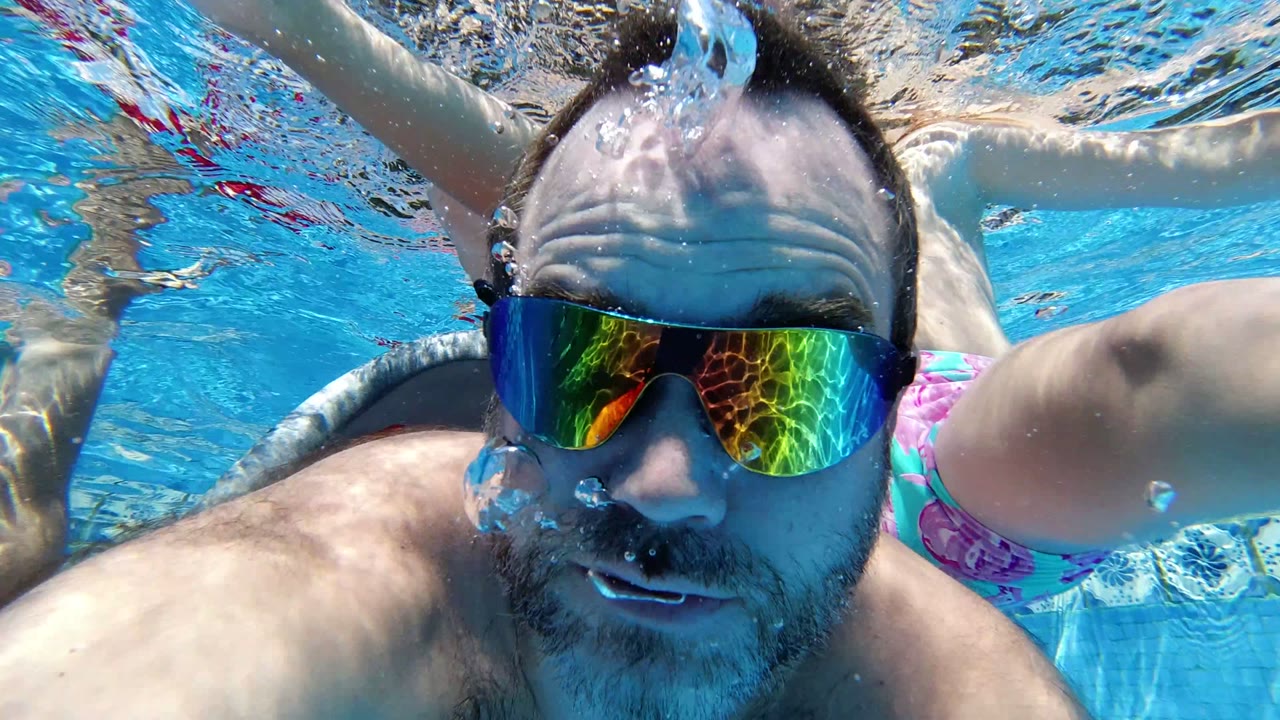 Father underwater in mirrored goggles with child swimming behind him.