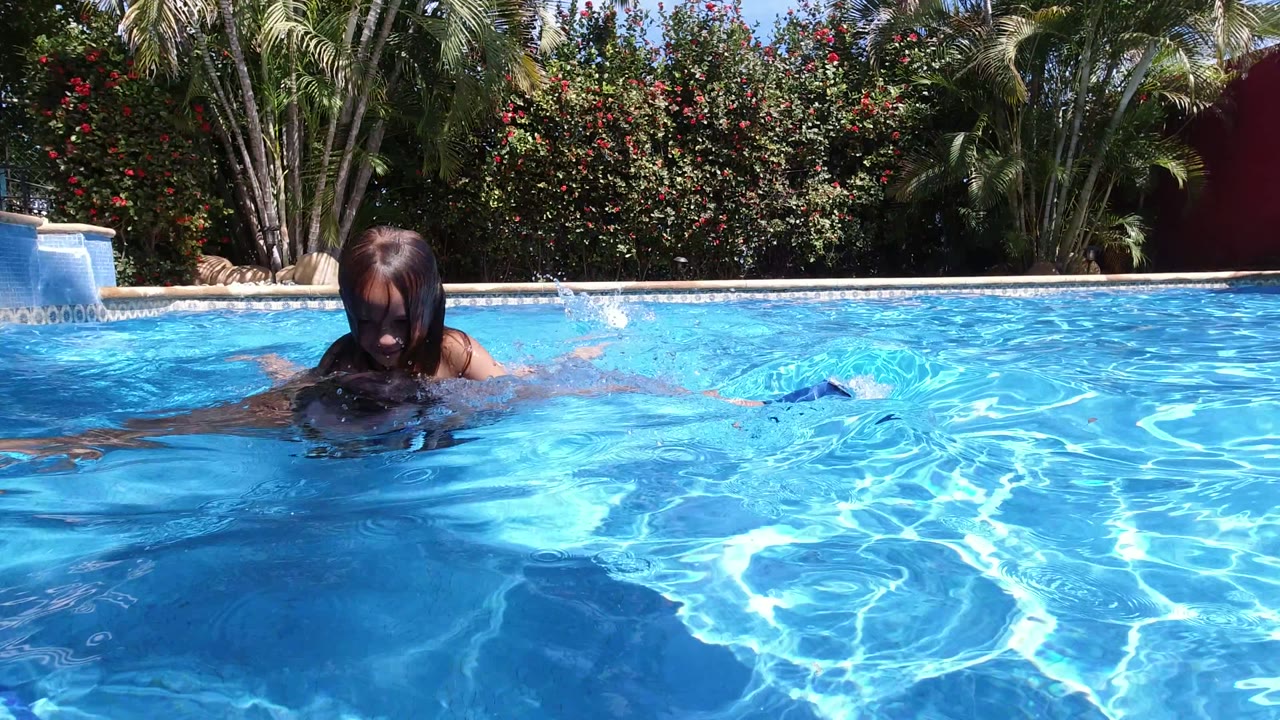 Young girl partly submerged in a blue swimming pool.
