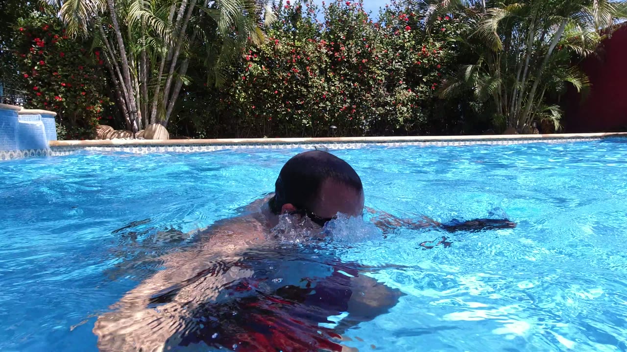 Man partly submerged in a bright blue swimming pool.