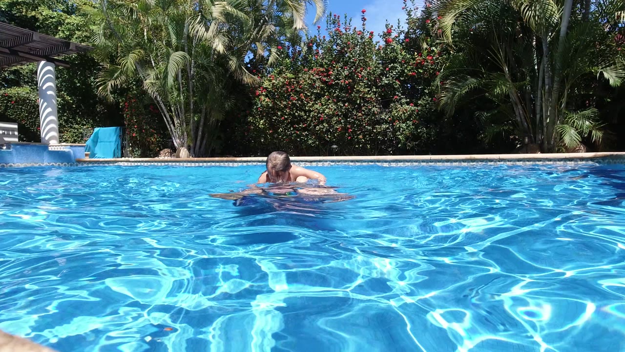 Father and child partly submerged in a blue swimming pool.