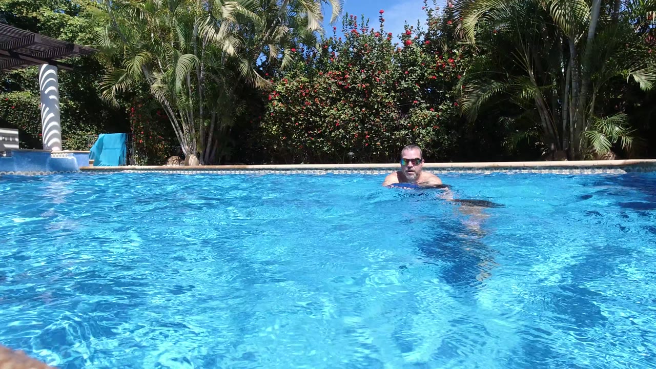 One second in, the man is centered in the Los Cabos pool while the child is mostly below the waterline or out of frame, with ripples filling the foreground.