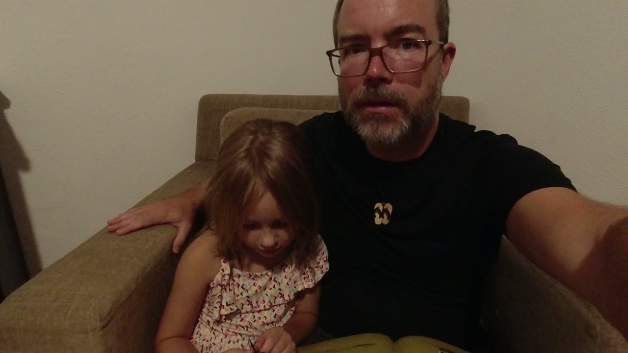 In Los Cabos, Mexico, the father faces the camera while the young girl looks down at the open book on their laps.