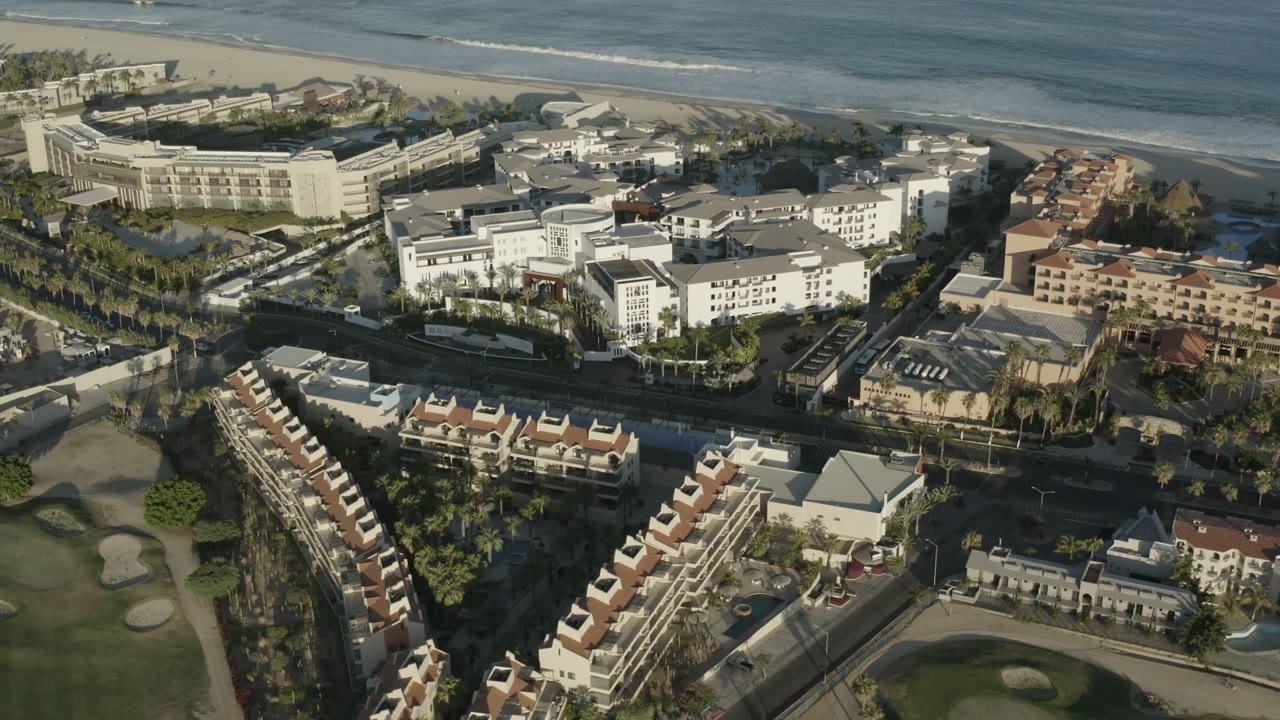 High aerial view of beachfront hotels, residential buildings, road, and surf.
