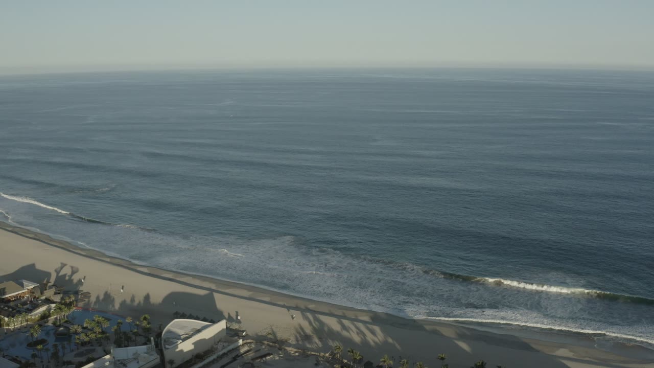 Wide aerial view of ash blue ocean meeting a sandy beach