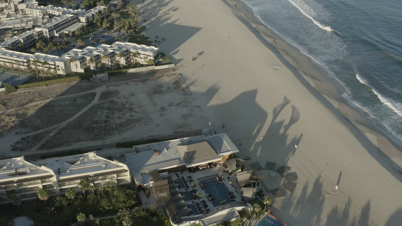 Aerial view of beachfront buildings, sand beach, and waves.