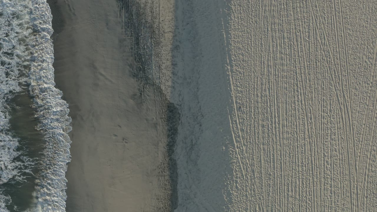 Overhead surf and marked sand on a beach.
