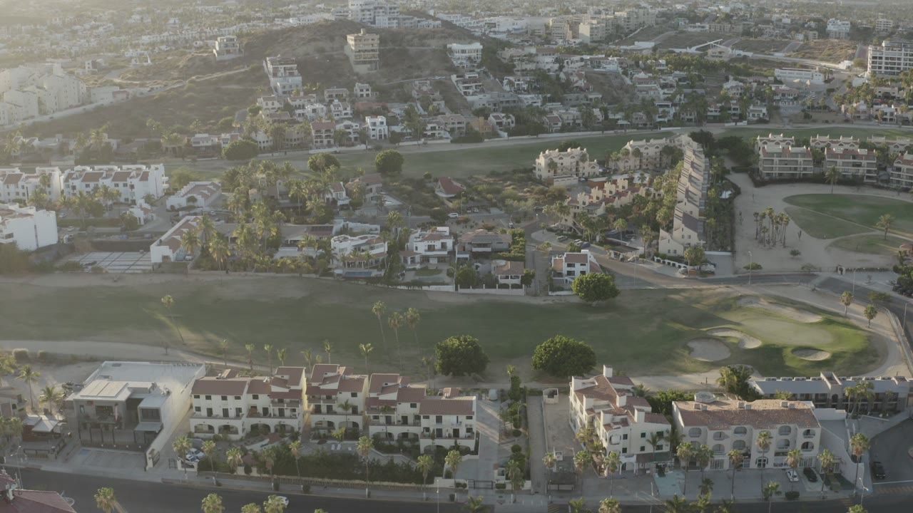 Aerial view of hotel roofs beside a golf course and surrounding buildings.
