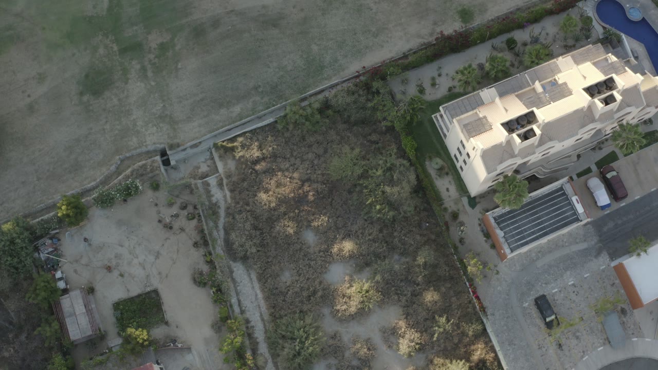 Overhead view of a pale building beside dry field and landscaping.