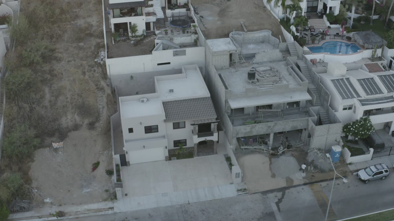Aerial view of modern homes beside a dry vacant lot and street.