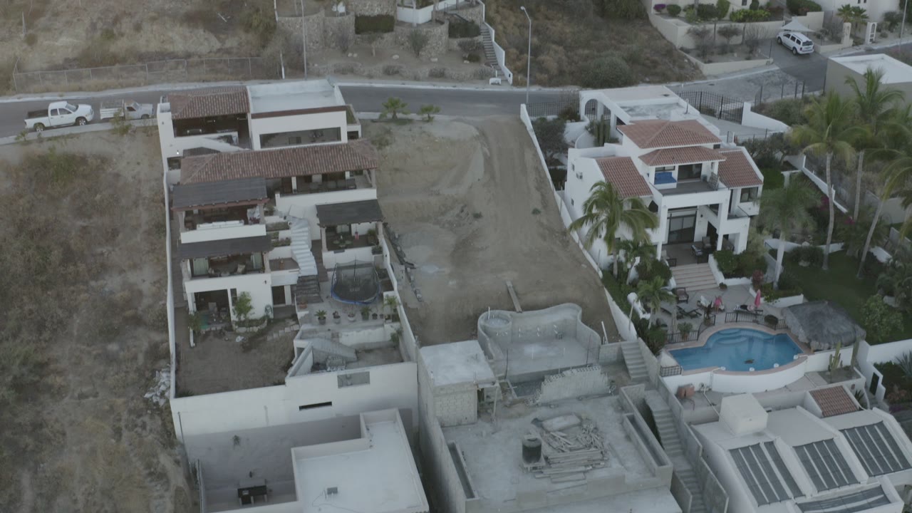 High aerial view of hillside villas, roads, palms, and a pool