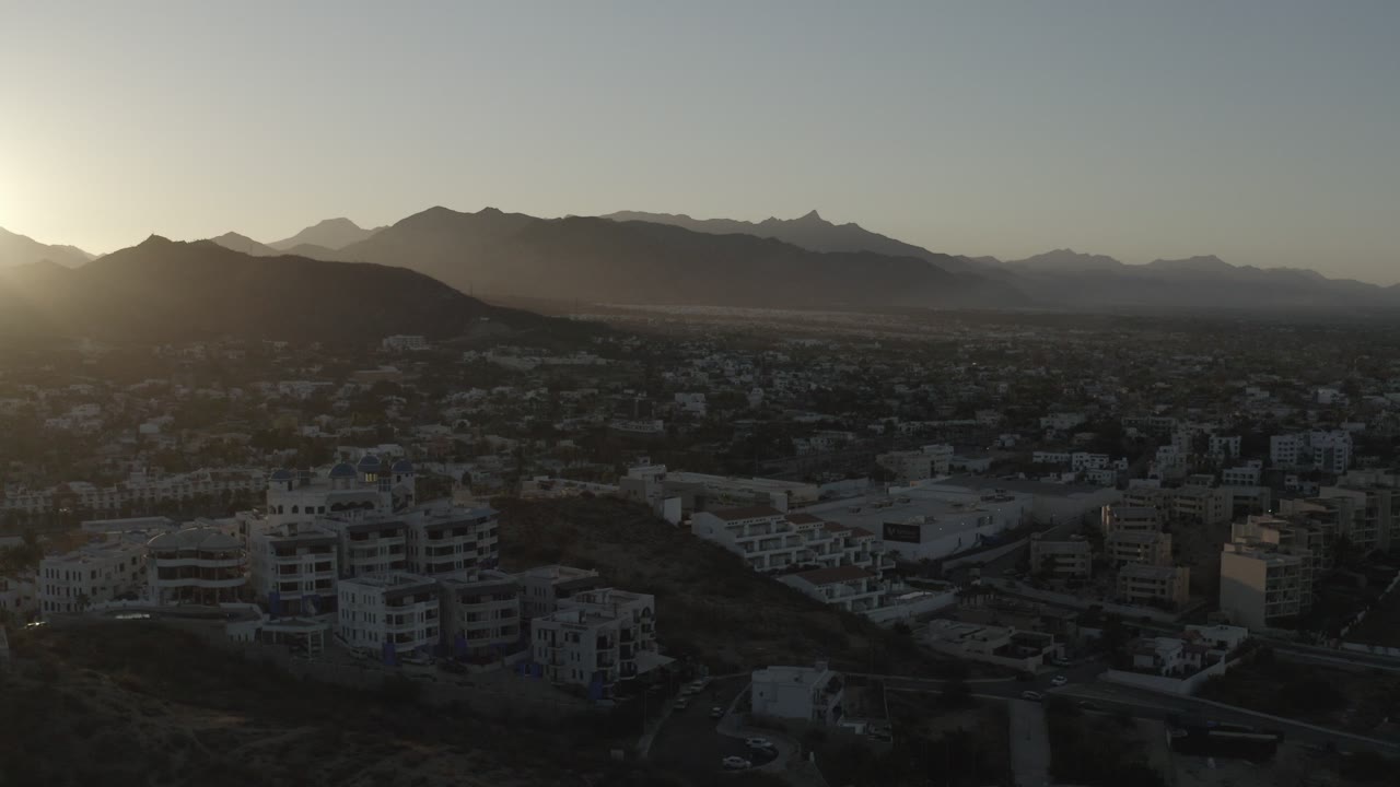 Sunrise over a city below dark mountains.