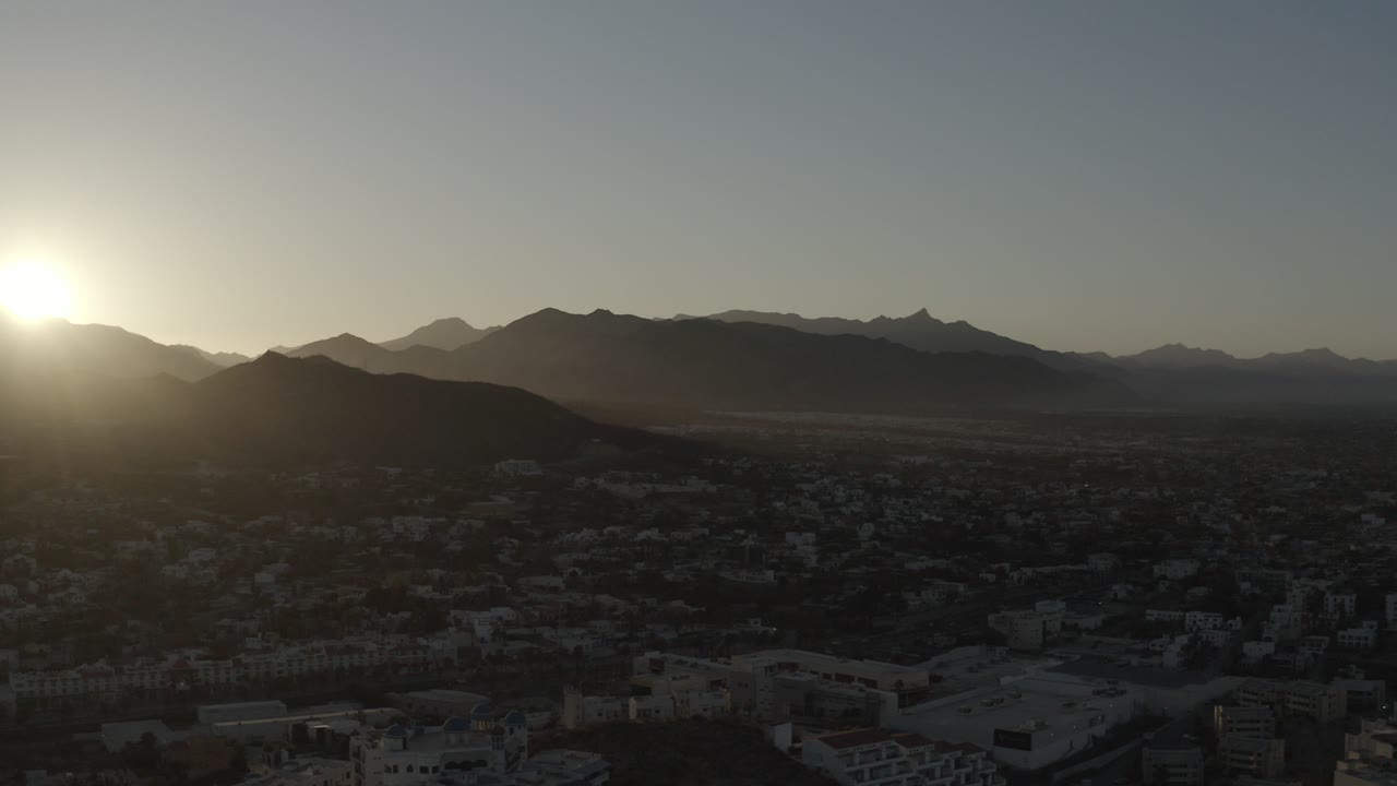 Aerial sunrise over a town and mountain ridge.