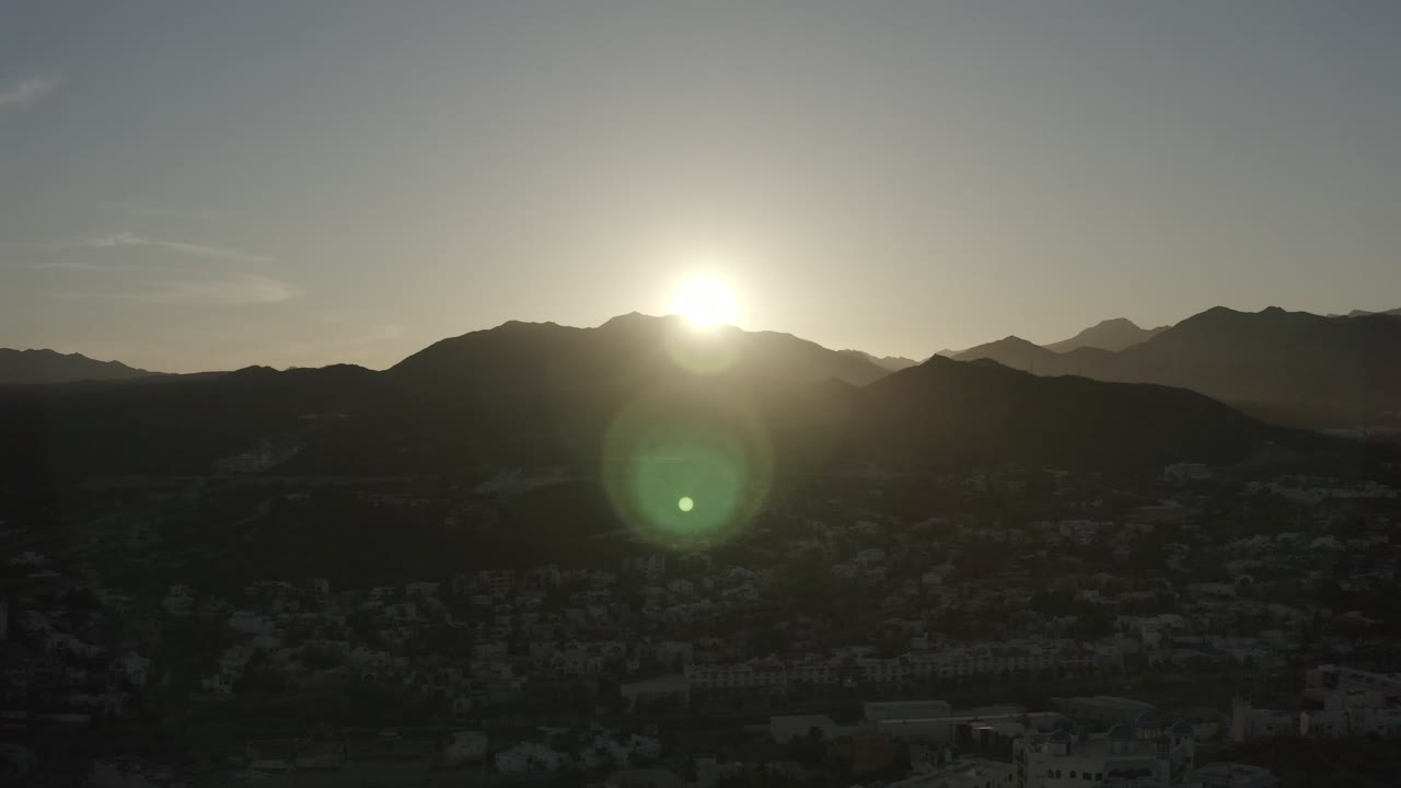Low sun over a dark mountain horizon with layered peaks.