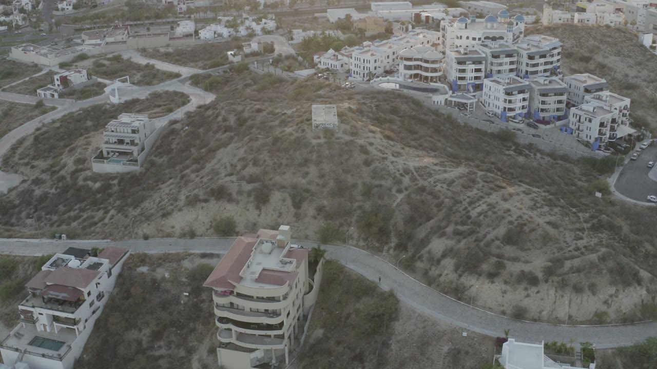 Aerial view of dry hillside with modern buildings and winding roads.