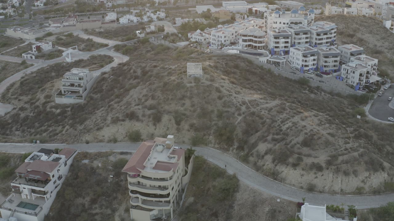 Elevated view of hillside roads and light-colored residential buildings.