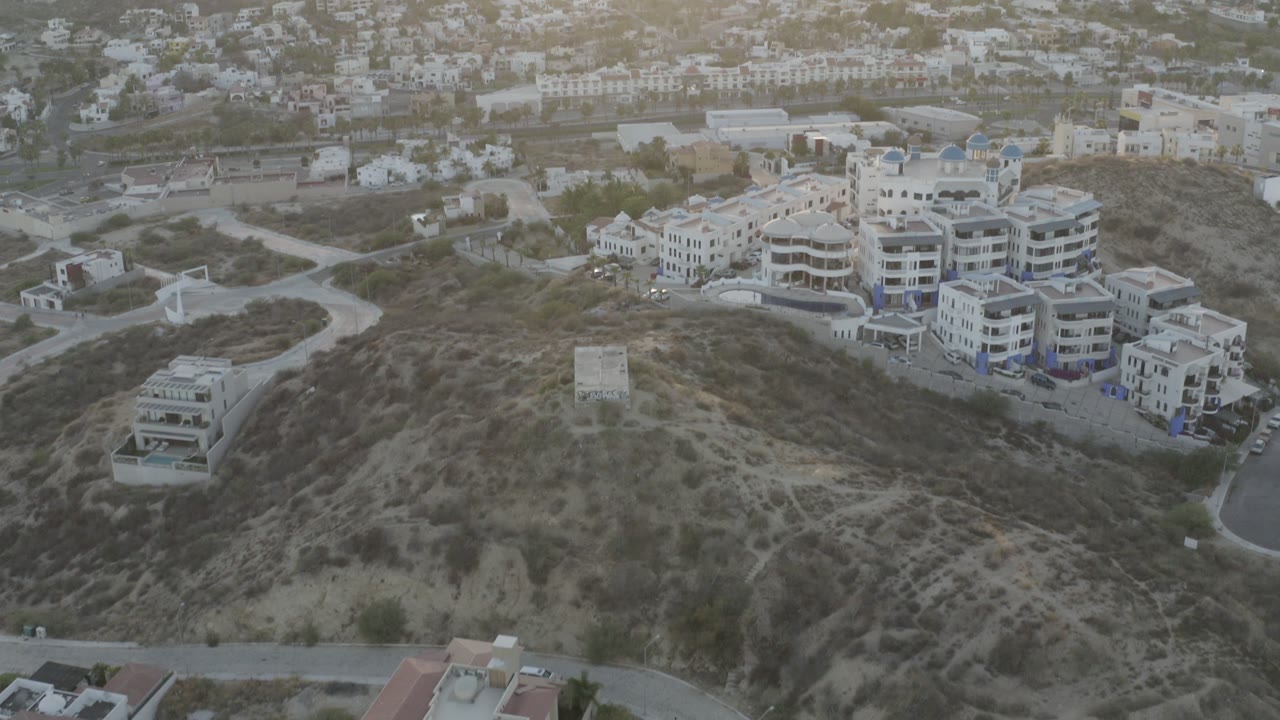 Aerial view of hillside homes and apartment buildings at low sun.