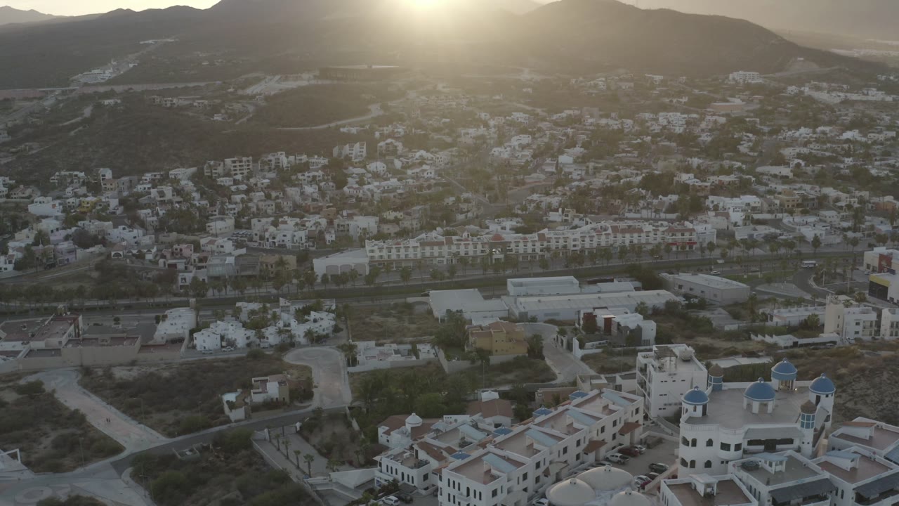 Aerial view of homes and hills under low sun glare.