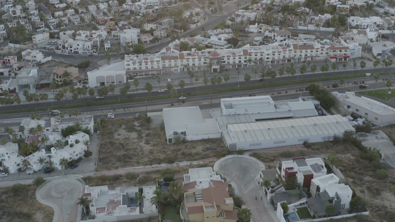 Aerial view of a divided highway, commercial buildings, homes, and hillside housing.