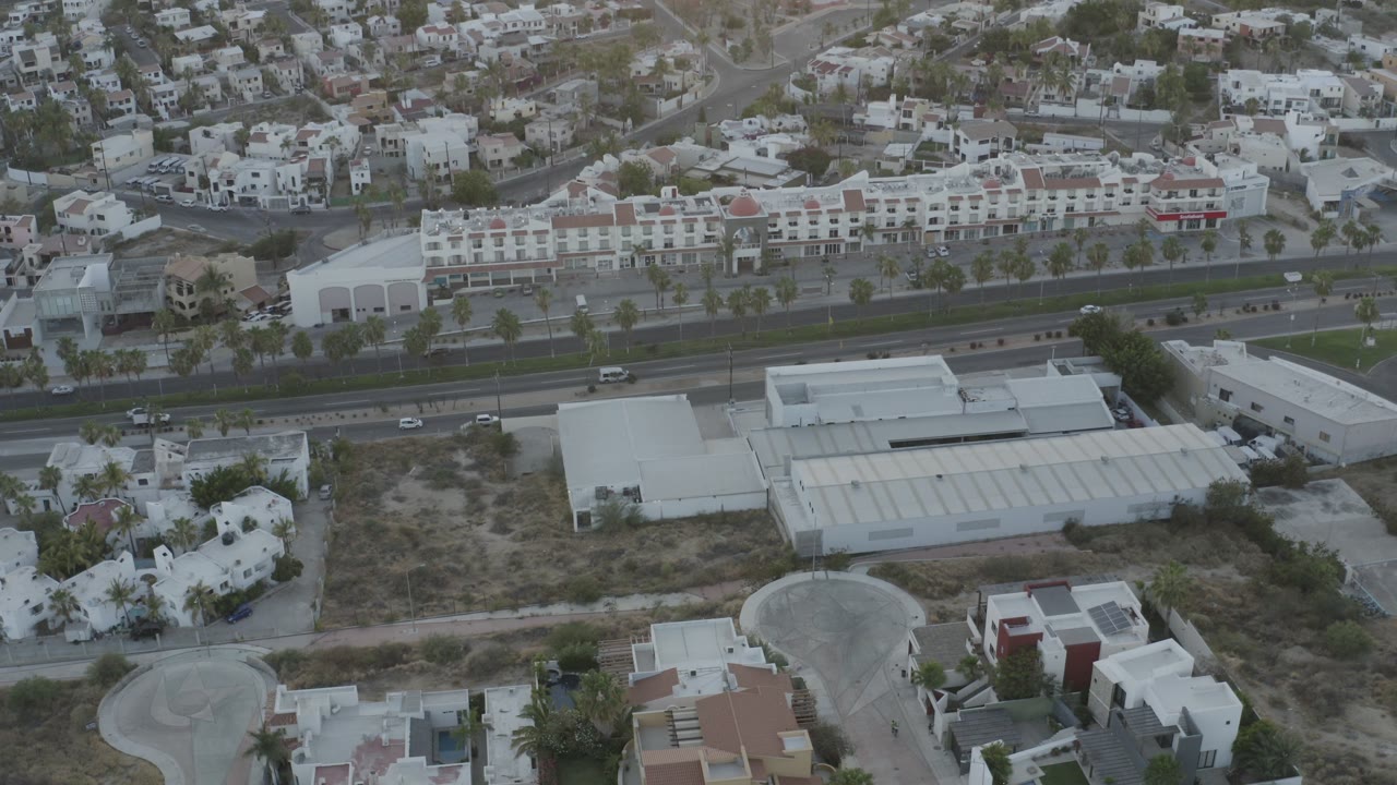 Aerial view of a road, buildings, and hillside homes.