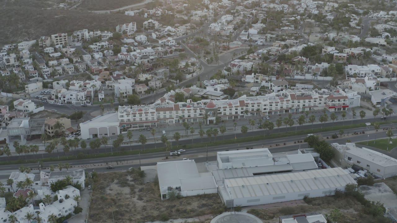 Overhead view across a highway toward white buildings and hillside housing.
