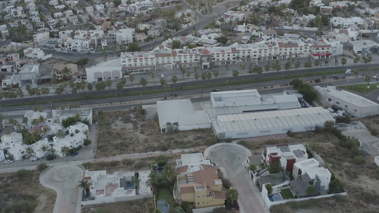 Aerial city view with residential villas, a broad road, and hillside neighborhoods.