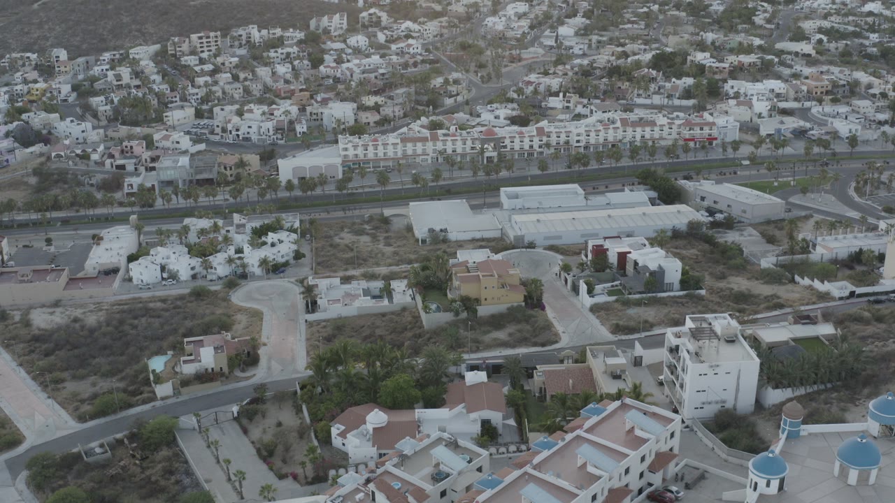 Aerial view of low-rise buildings, roads, and hillside homes.