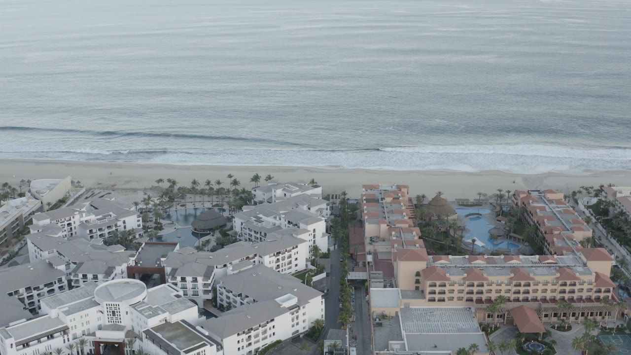 Aerial view of beachfront buildings beside ocean surf.