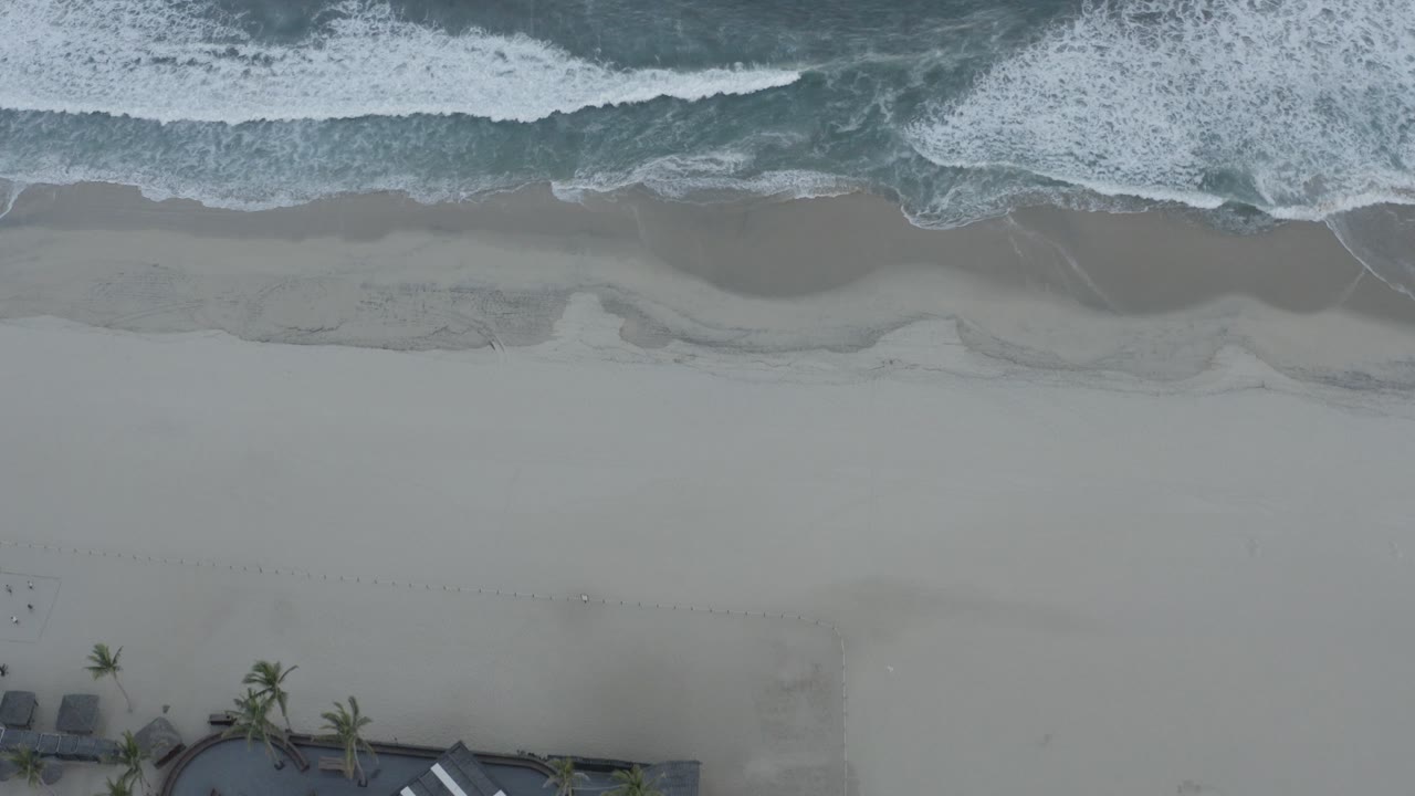 Overhead surf washing onto a pale sandy beach