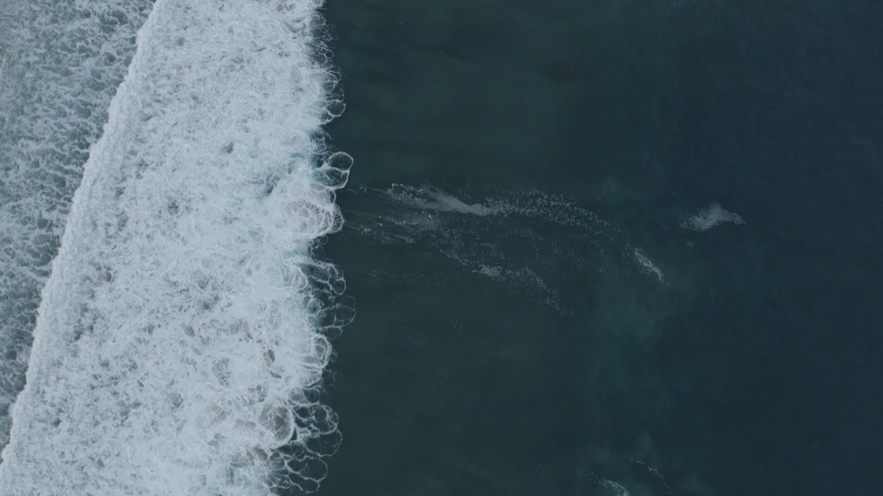 Los Cabos overhead surf frame with dense white foam pushed farther across the left half and calmer dark water on the right, no visible people.