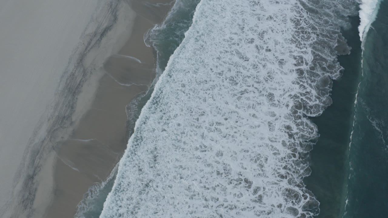 Overhead surf breaking beside wet sand
