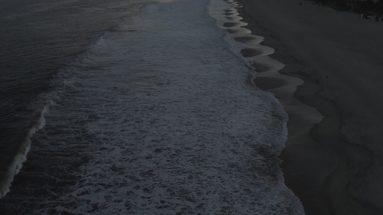 Breaking wave edge beside wet beach